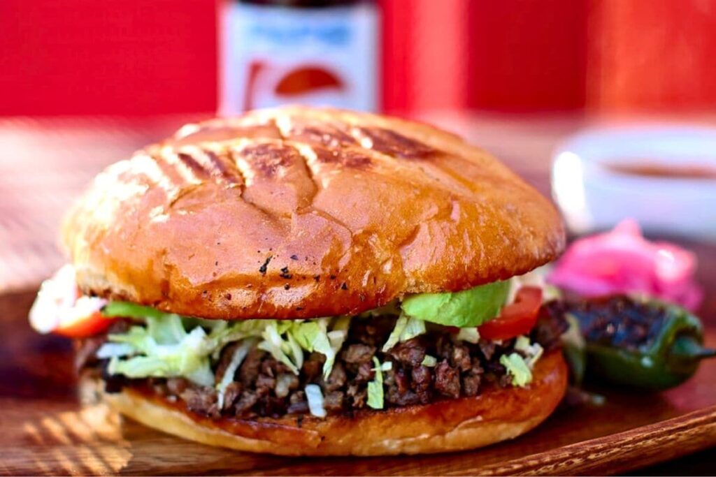 Carne asada torta with lettuce, tomato, avocado, and mayo