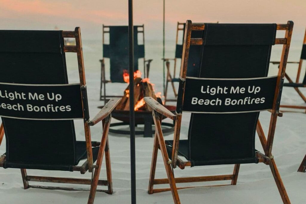 Light Me Up Beach Bonfires chairs around a bonfire at dusk