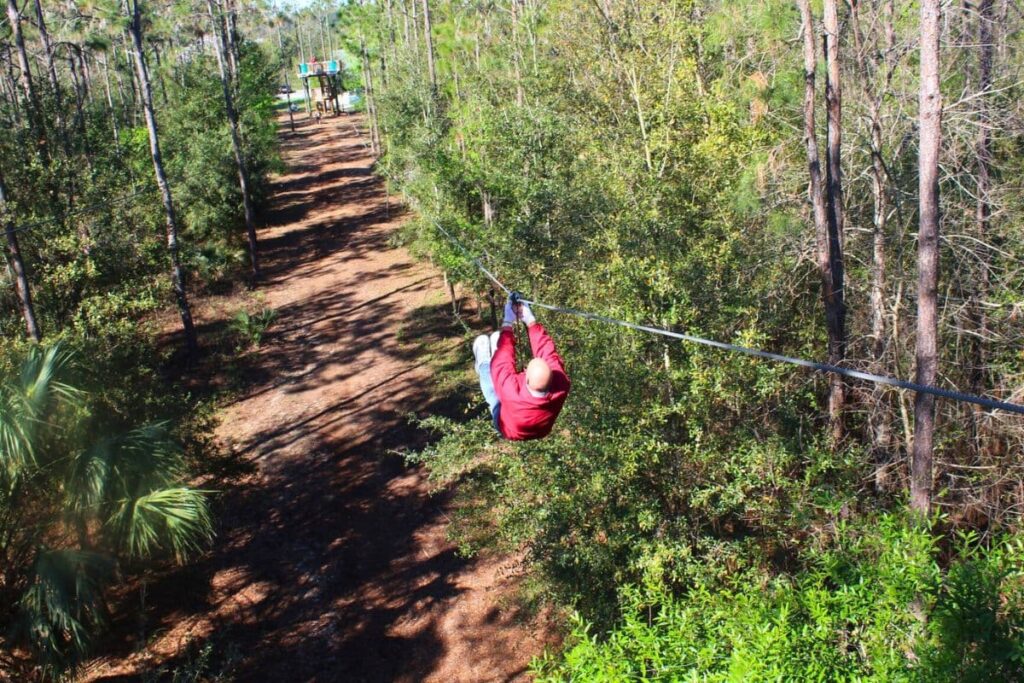 Man ziplining down between the trees at Orlando Tree Trek