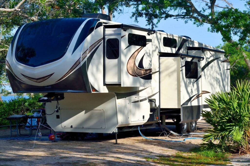 white and black RV camper under trees