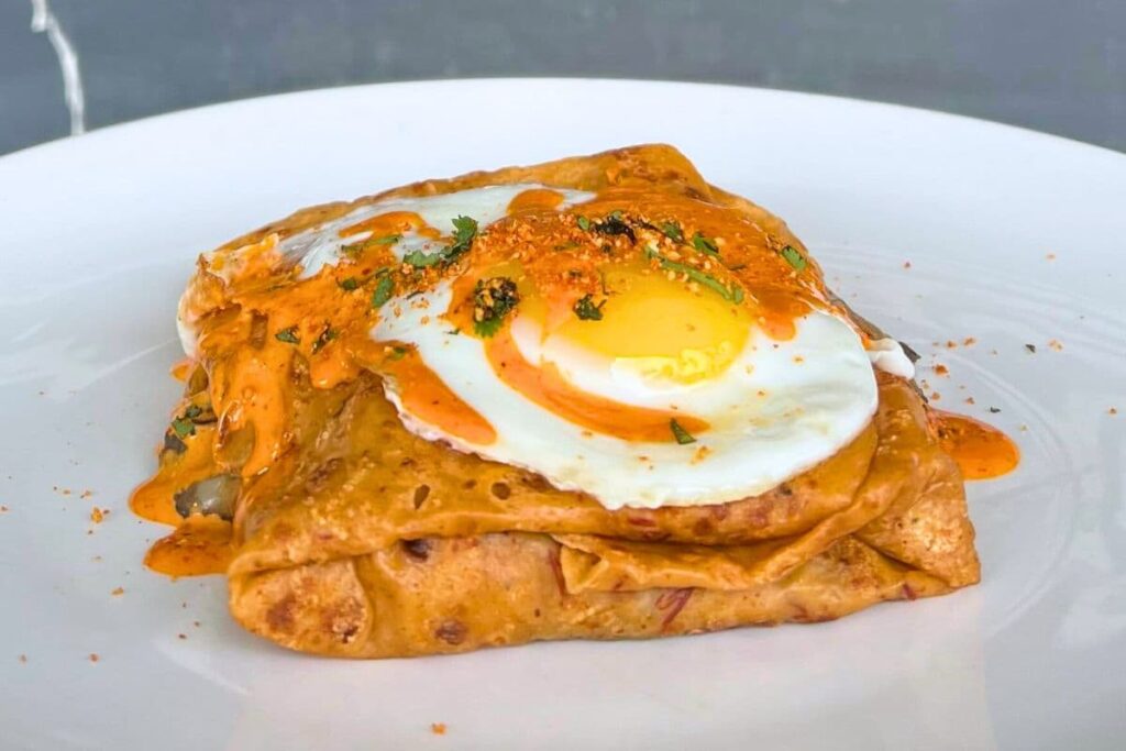 Chef's special breakfast crepe roasted chicken enchilada topped with a fried egg